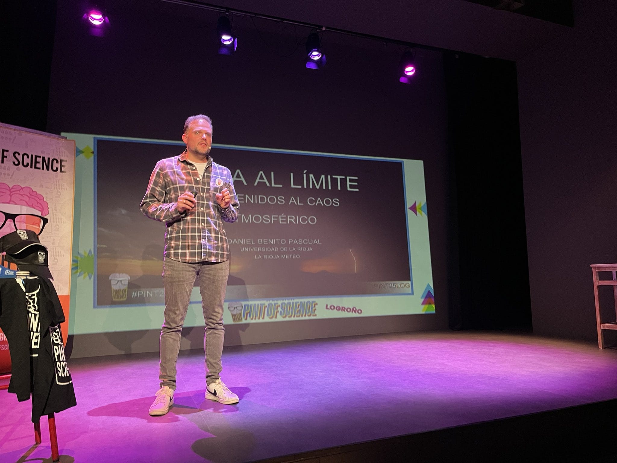 Damniel Benitohablando en el festival Pint of Science sobre el cambio climático, con una presentación en pantalla que dice 'Clima al límite: bienvenidos al caos atmosférico'.