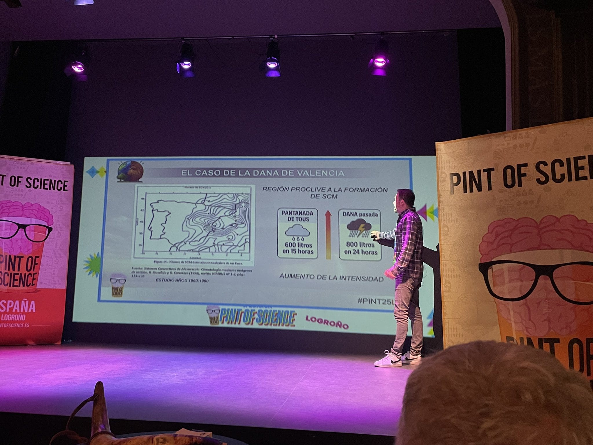 Daniel Benito explicando el caso de la DANA en Valencia durante el festival Pint of Science, con gráficos sobre la formación de fenómenos meteorológicos y datos de precipitaciones.